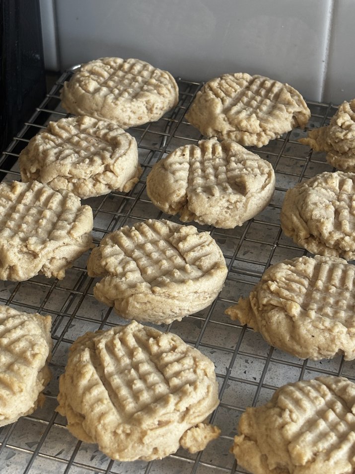 Galletas de mantequilla de cacahuete con masa madre enfri&aacute;ndose sobre una rejilla.